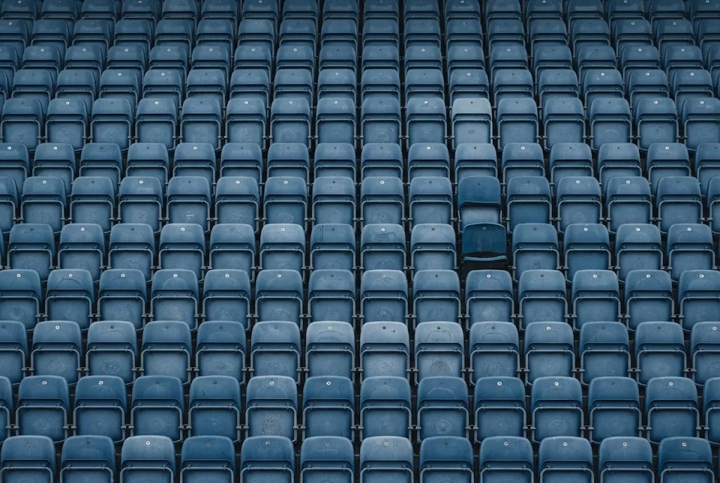 Rows of empty blue stadium seats photographed straight on in flat daylight