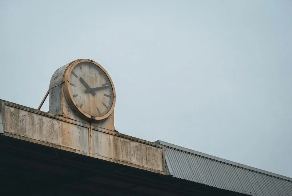 A large stadium clock face against a plain sky above an empty stand