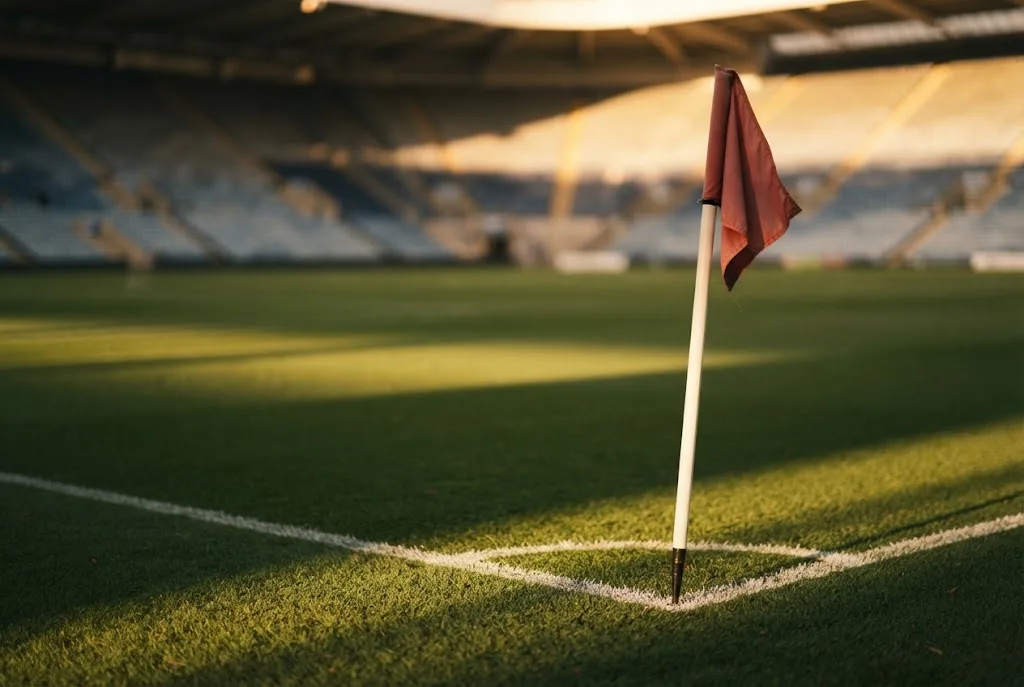 A corner flag and painted touchline on a well-kept pitch in low autumn sun